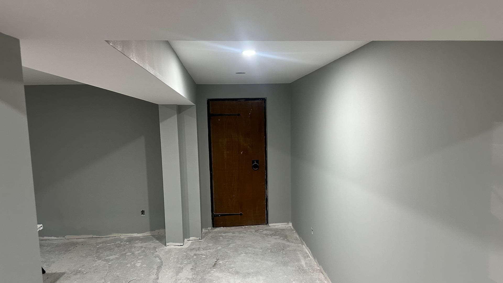 Finished grey drywall walls, bulkhead, and wood door from a residential basement finish