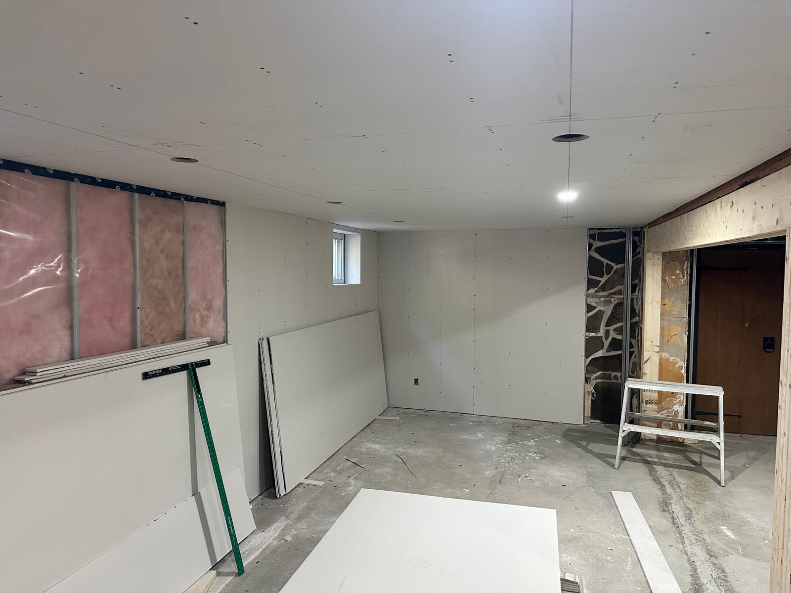 Drywall hang in progress with metal framing and insulation visible