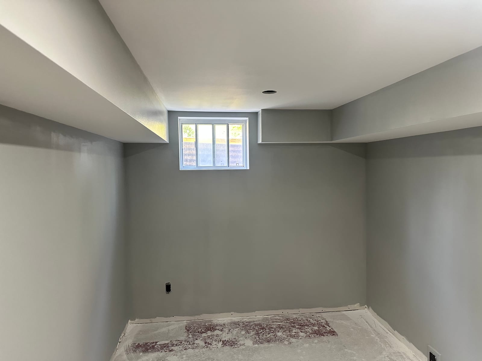 Finished grey walls, white bulkheads, and basement window ready for trim