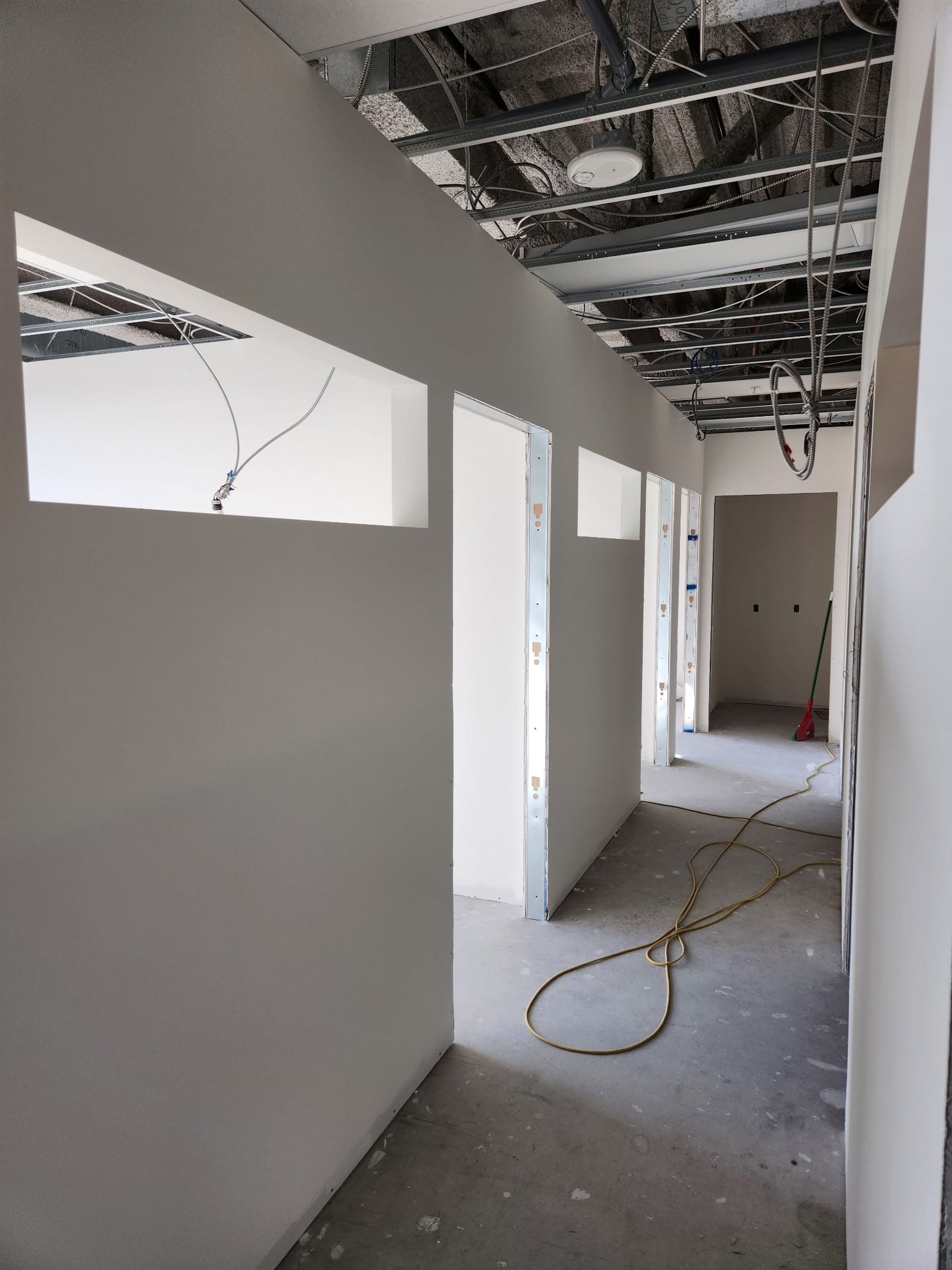 Office-style partitions and drywall hallway with exposed ceiling grid