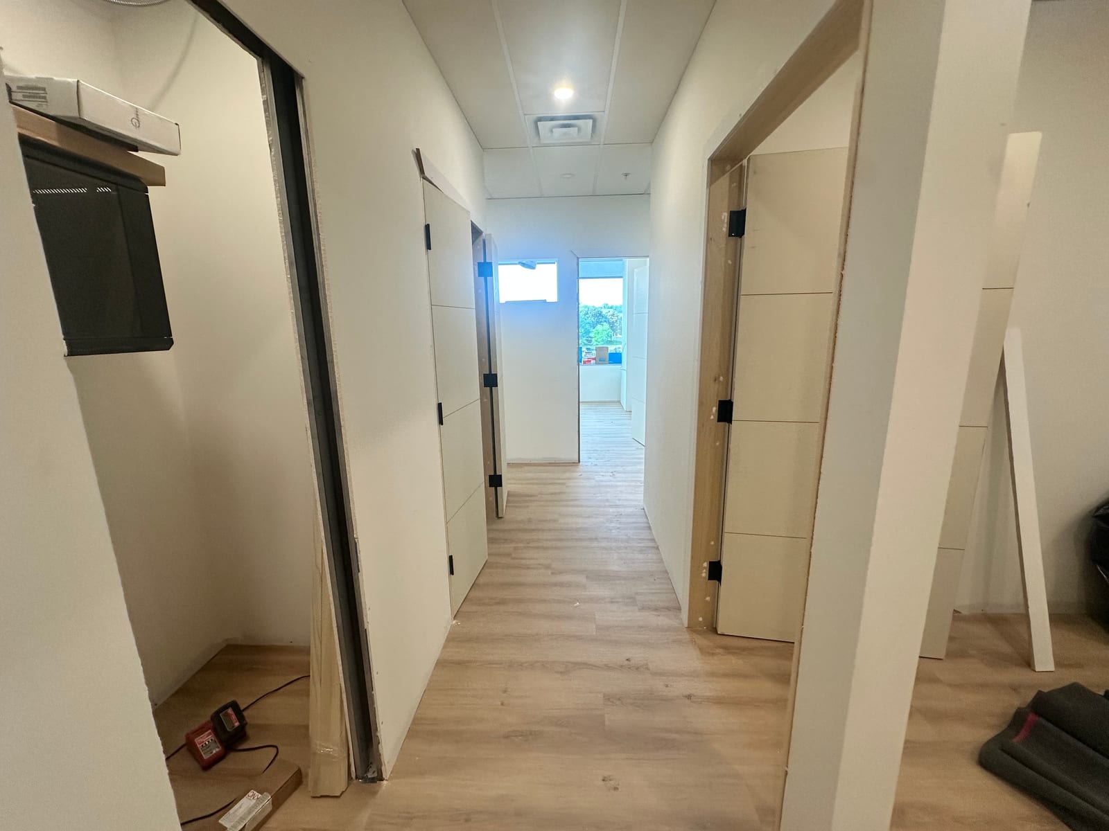 Long hallway with finished drywall, T-bar ceiling, and doors